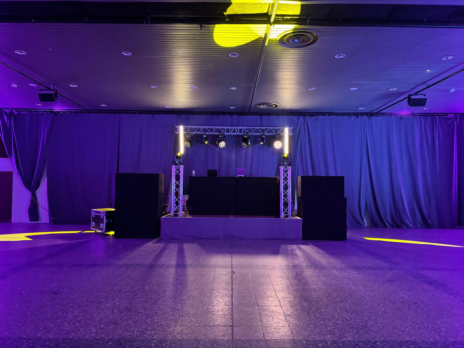 Saal mit lila Licht und DJ-Pult