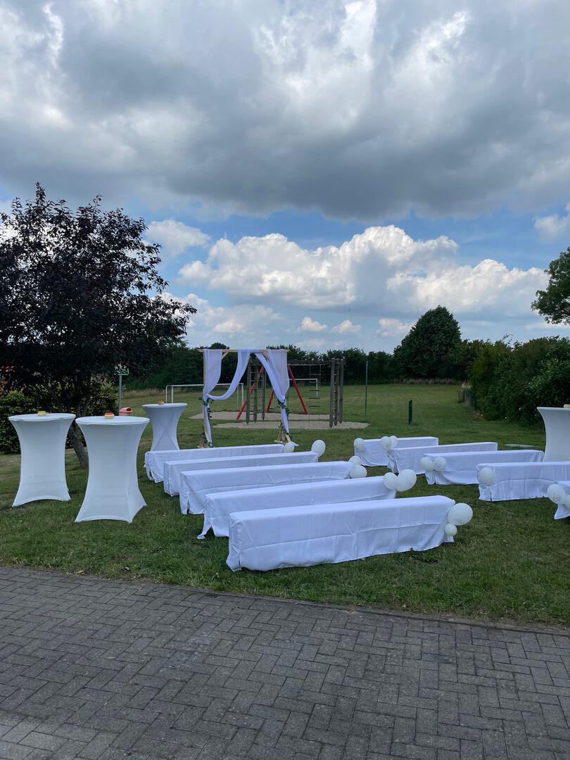 Stuhlreihen mit weißen Hussen im Garten